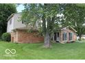 Back view of home with screen room, brick accents, and a large tree at 8905 Maze Rd, Indianapolis, IN 46259