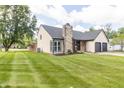 Charming house with a stone chimney, green lawn, colorful flowers, and a lovely landscape at 8925 Sunburst Cir, Indianapolis, IN 46227