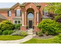 Inviting front entrance with a brick archway, decorative pillars, flowering planters, and a well-manicured lawn at 9237 Rocky Cay Ct, Zionsville, IN 46077