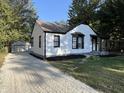 Exterior view of home with white siding, black trim, gravel drive, and detached garage at 937 N Routiers Ave, Indianapolis, IN 46219