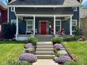 Inviting front porch with a red door, white columns, seating, and manicured landscaping at 1105 Windsor St, Indianapolis, IN 46201