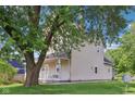 Side view of a two-story home with a covered porch, surrounded by mature trees and a well-kept lawn at 1129 Trowbridge St, Indianapolis, IN 46203