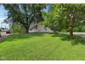 Expansive front yard featuring lush green grass and mature trees providing shade and privacy at 1129 Trowbridge St, Indianapolis, IN 46203