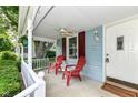 Cozy front porch with white columns and inviting red Adirondack chairs at 114 South St, Southport, IN 46227