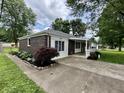 Charming brick home with a covered front porch, nicely landscaped yard and concrete driveway at 1400 Evelyn Ln, Anderson, IN 46017