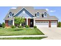 Charming two-story brick home with a three-car garage, blue siding, and manicured lawn at 21536 Gisborne Dr, Noblesville, IN 46062