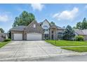 Traditional two-story home featuring a manicured lawn, brick facade, and an attached two-car garage at 2463 Kettering Way, Indianapolis, IN 46214