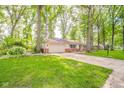 Single-story home with attached garage and beautiful green lawn and mature trees at 2613 W Queensbury Rd, Muncie, IN 47304