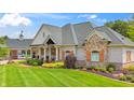 Charming home featuring brick and stone accents, a covered porch, and manicured lawn at 3399 Nottinghill Blvd, Plainfield, IN 46168