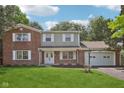 Charming two-story brick home with a well-manicured lawn and attached two-car garage at 6838 Johnson Rd, Indianapolis, IN 46220