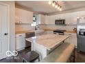 Bright eat-in kitchen boasts white cabinetry, butcher block countertops, and a stylish marble island at 774 Courtney Cir, Danville, IN 46122