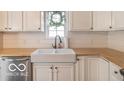 Close up on a white farmhouse sink and butcher block countertops in the bright kitchen at 774 Courtney Cir, Danville, IN 46122