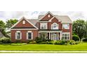 Beautiful two-story brick home with a lush green lawn and colorful flower beds at 10480 Stonegate Dr, Fishers, IN 46040