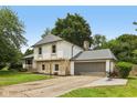 Charming two-story home with a stone facade, mature trees, and a paved driveway to the attached garage at 10778 Haverstick Rd, Carmel, IN 46033
