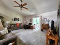 Bright living room with neutral carpet, ceiling fan, and sliding glass doors at 1223 Long Shore Dr, Indianapolis, IN 46217