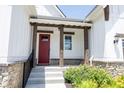 Inviting covered porch with stone accents and a bright red front door, enhanced by colorful landscaping at 1872 Wellpark Dr, Westfield, IN 46074
