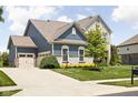 Rear exterior view showcasing the home's blue siding, stone accents, attached garage and expansive driveway at 3720 Abney Highland Dr, Zionsville, IN 46077