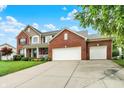 Charming two-story brick home with a well-manicured lawn, beautiful landscaping, and a three car attached garage at 564 Gainesway N Dr, Greenwood, IN 46142
