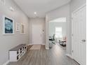 Welcoming entryway with light gray walls, wood-look flooring, bench, shoe rack, and contemporary decor at 5809 Terracotta Trce, McCordsville, IN 46055