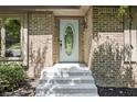 Brick home entrance with a white door featuring an oval window, concrete steps, and dark mulch landscaping at 604 Oak Blvd W Dr, Greenfield, IN 46140