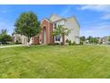 Charming two-story home with a well-manicured lawn, a three-car garage and a red brick facade at 7350 Gold King Way, Indianapolis, IN 46259