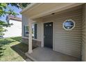 Inviting front porch with decorative window, gray siding, white pillar and a green shuttered window at 10222 Arapahoe Dr, Indianapolis, IN 46235