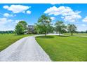 Scenic view of a house featuring a long driveway, spacious lawn, and mature trees under a bright sky at 11250 N 600 W, Fountaintown, IN 46130