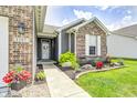 Close-up of charming front door with decorative wreath, beautiful landscaping and a well-lit walkway at 1187 Blackthorne S Trl, Plainfield, IN 46168