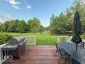 Inviting back deck featuring a grill, outdoor dining set, and serene backyard views at 13221 Griffin Run, Carmel, IN 46033