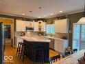 Bright kitchen features white cabinets, stainless steel appliances, kitchen island with breakfast bar and wood floors at 13221 Griffin Run, Carmel, IN 46033