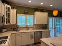 Kitchen featuring white cabinets, stainless steel appliances, a kitchen sink below a large window, and wood floors at 13221 Griffin Run, Carmel, IN 46033
