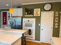 Kitchen shows stainless steel refrigerator and wall oven surrounded by white cabinets, with a clock hanging above a door at 13221 Griffin Run, Carmel, IN 46033