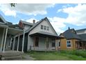 Exterior view of a two-story home with a covered porch among other houses needing renovation at 1601 Spann Ave, Indianapolis, IN 46203