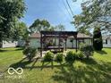 Backyard featuring a pergola with a picnic table and lush landscaping at 1919 Manor Dr, Lebanon, IN 46052