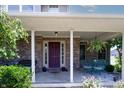 Inviting front porch with cozy seating, brick accents, hanging plants and a colorful front door at 2756 Bluebell E Ct, Columbus, IN 47201