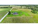 Wide aerial view of tan home with American flag, shed, and playset, nestled among fields and trees at 3450 Clay Rd, North Salem, IN 46165