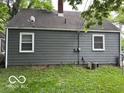 View of home's backyard with grey siding, a grassy yard, and trees providing shade at 4405 Primrose Ave, Indianapolis, IN 46205