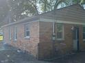 Rear exterior view of the brick home featuring a side entrance, windows, and partial fencing at 4723 Crittenden Ave, Indianapolis, IN 46205