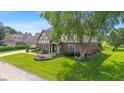 Beautiful front yard showcasing a Tudor-style home with mature landscaping and a water fountain at 625 La Placita St, Greenwood, IN 46143