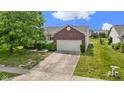 A well-maintained home featuring a two-car garage, long driveway, and mature landscaping at 8778 N Deer Crossing Blvd, McCordsville, IN 46055