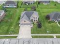 Expansive aerial view of a brick two-story home with a well-manicured lawn and mature trees at 1035 White Oak Dr, Plainfield, IN 46168