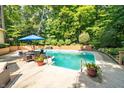 Inviting in-ground pool surrounded by lush greenery and a comfortable seating area under a blue umbrella at 10518 Courageous Dr, Indianapolis, IN 46236