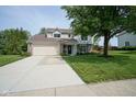 Traditional home featuring a two-car garage, lush lawn, mature tree, and welcoming front entrance at 13074 Lansdowne Dr, Fishers, IN 46038