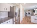 Well-lit kitchen with stainless steel refrigerator, white cabinets, granite countertops, and wood-look flooring at 13074 Lansdowne Dr, Fishers, IN 46038