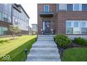 Home's entry features a welcoming flower wreath, planters, and concrete steps leading to the front door at 13301 Minden Dr, Fishers, IN 46037