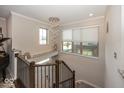 Hallway showcasing a modern chandelier, staircase with metal railings, and natural light from nearby windows at 13301 Minden Dr, Fishers, IN 46037