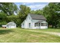 Quaint white home with a sunroom and detached garage on a meticulously maintained green lawn at 16000 W 700 S, Anderson, IN 46017