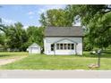 Charming white home featuring a sunroom, set on a well-manicured lawn with an adjacent garage at 16000 W 700 S, Anderson, IN 46017