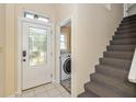 Bright entryway featuring a decorative front door, adjacent stairs and a view into the laundry room at 19522 Diamond Way, Noblesville, IN 46062
