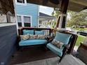 Relaxing front porch featuring a bench, chair, and table decorated with light blue cushions and pillows with floral prints at 3054 Ruckle St, Indianapolis, IN 46205